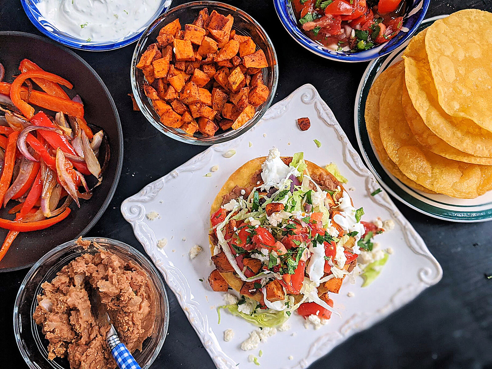 These vegetarian tostadas are stacked with two layers of smashed pinto beans, lettuce, pico and roasted sweet potatoes and bell peppers.
